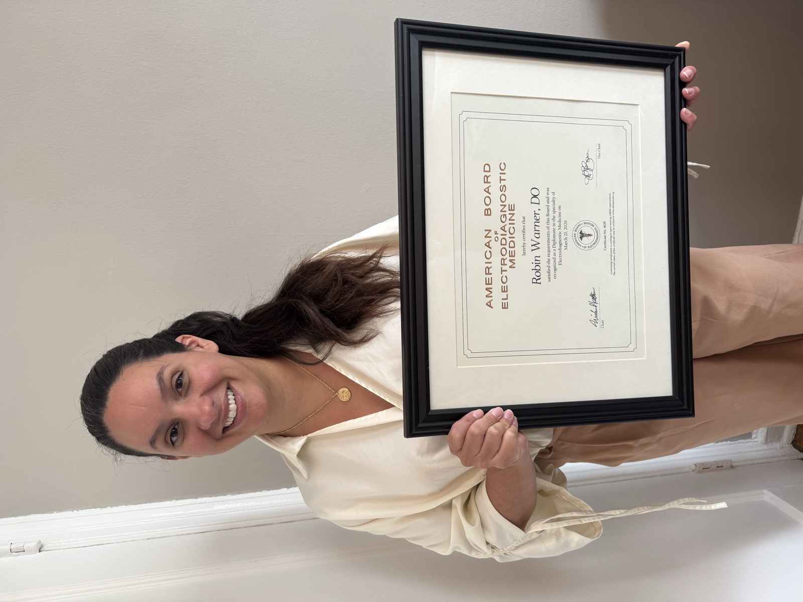 Dr. Robin Warner holding her American Board of Electrodiagnostic Medicine certification